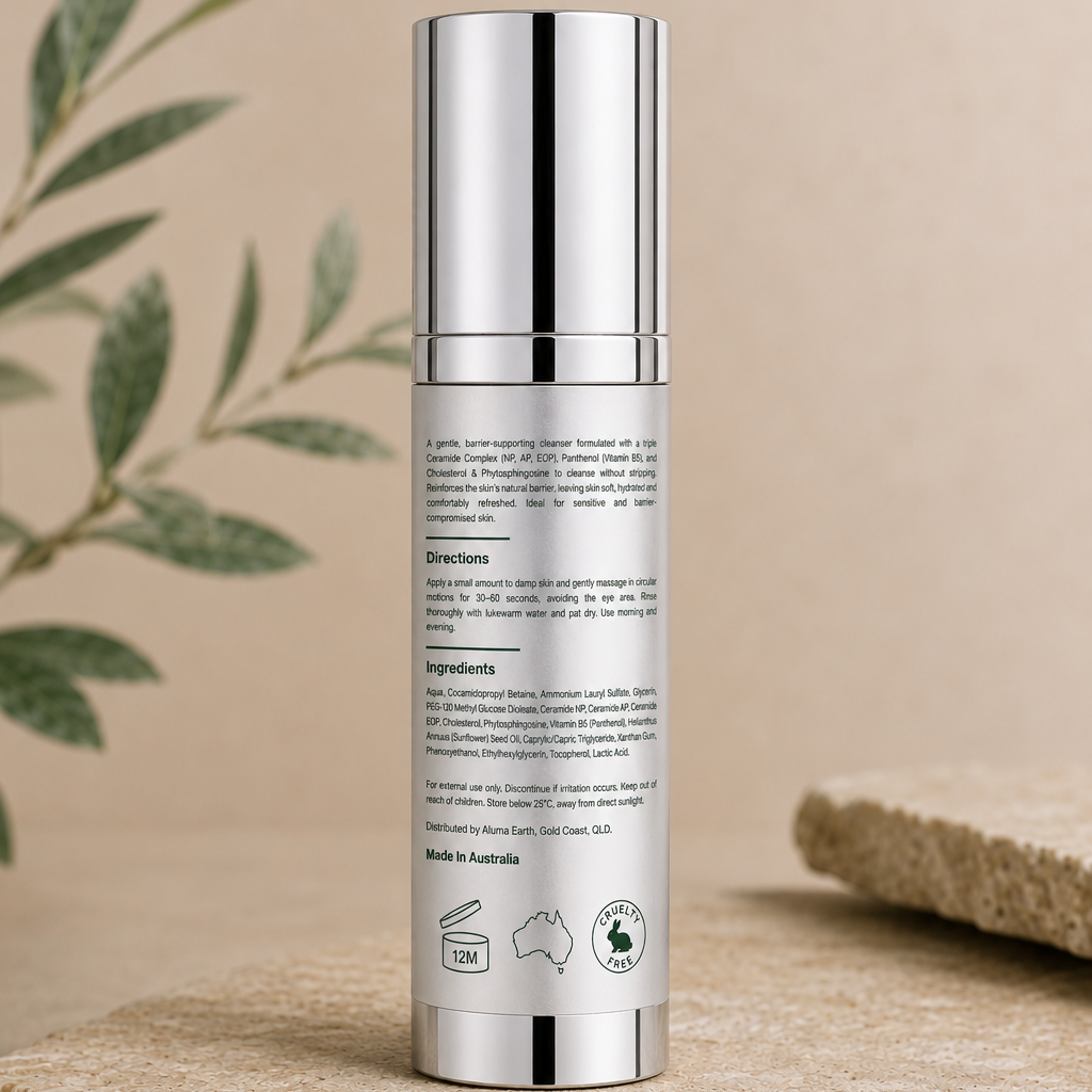 Silver skincare bottle on a beige surface with a plant in the background